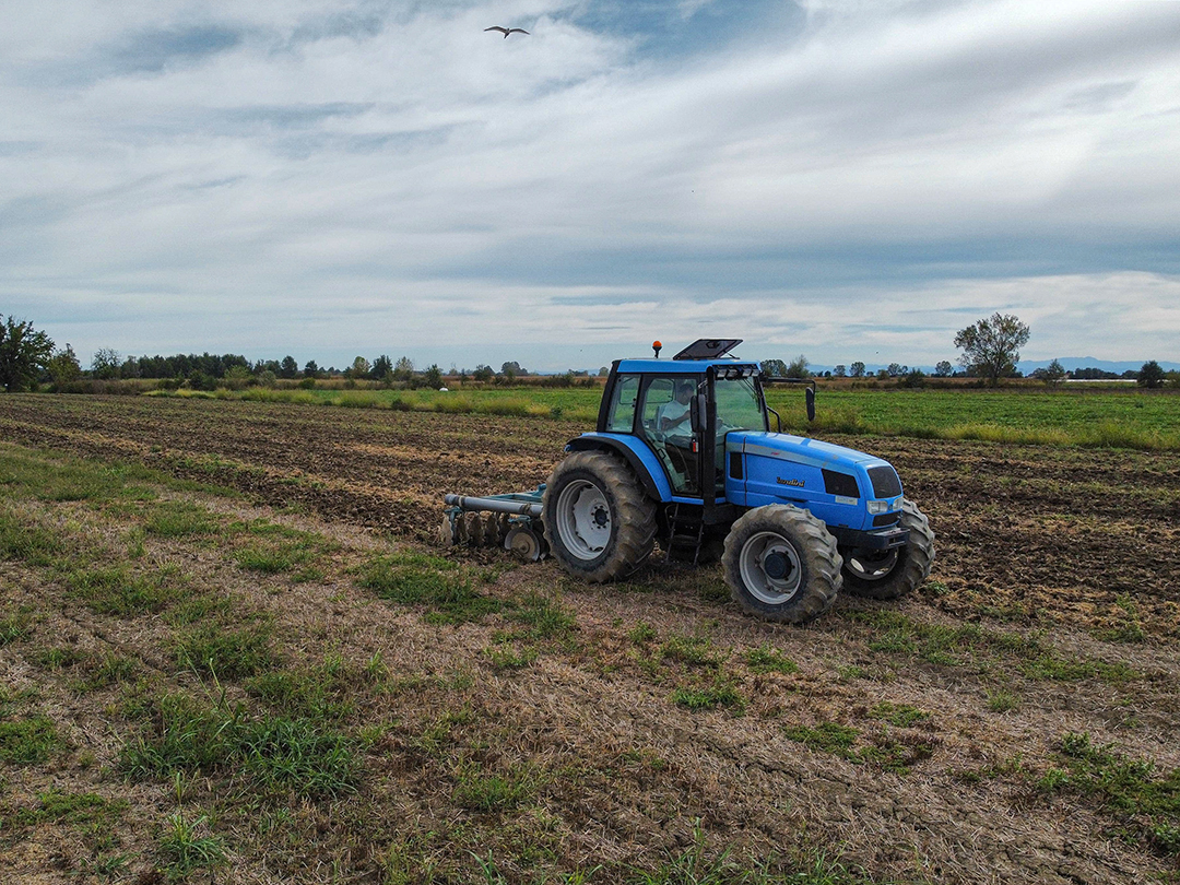 Farm tractor with disc harrow in open field